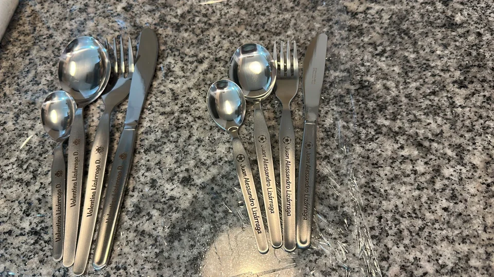 Dos sets de cubiertos personalizados sobre una mesa