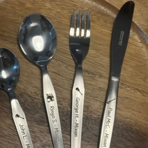 Set de cubiertos con nombres grabados sobre una tabla de madera